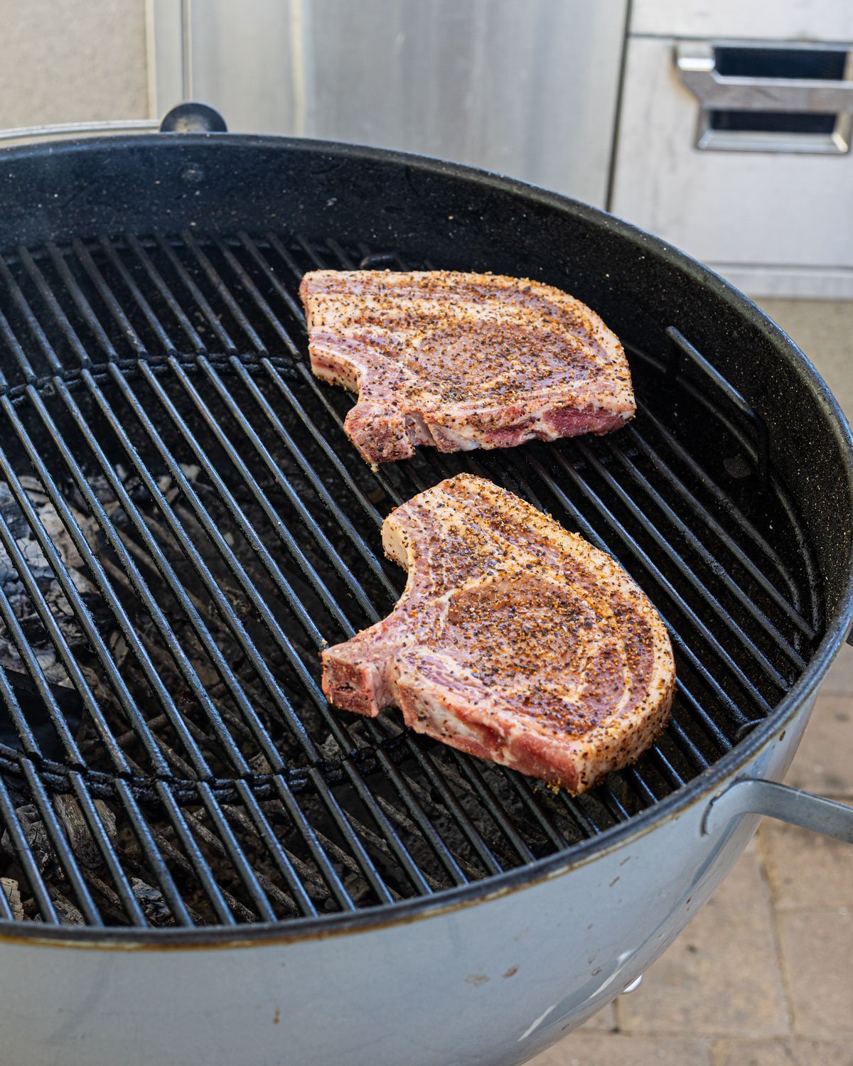 Two large bone-in pork chops on the indirect heat side of the grill.