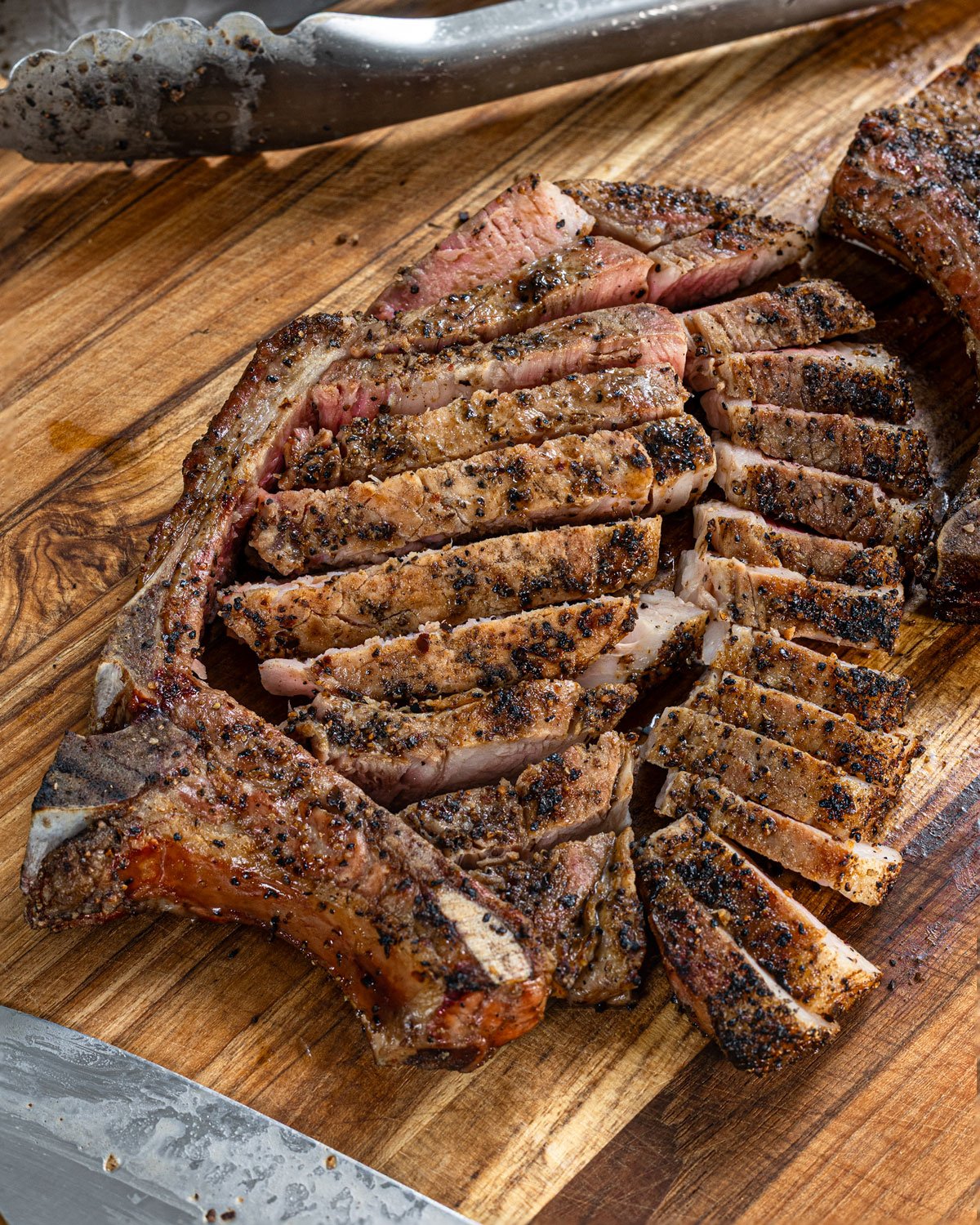Smoked bone-in pork chop sliced into pieces on a wooden board.