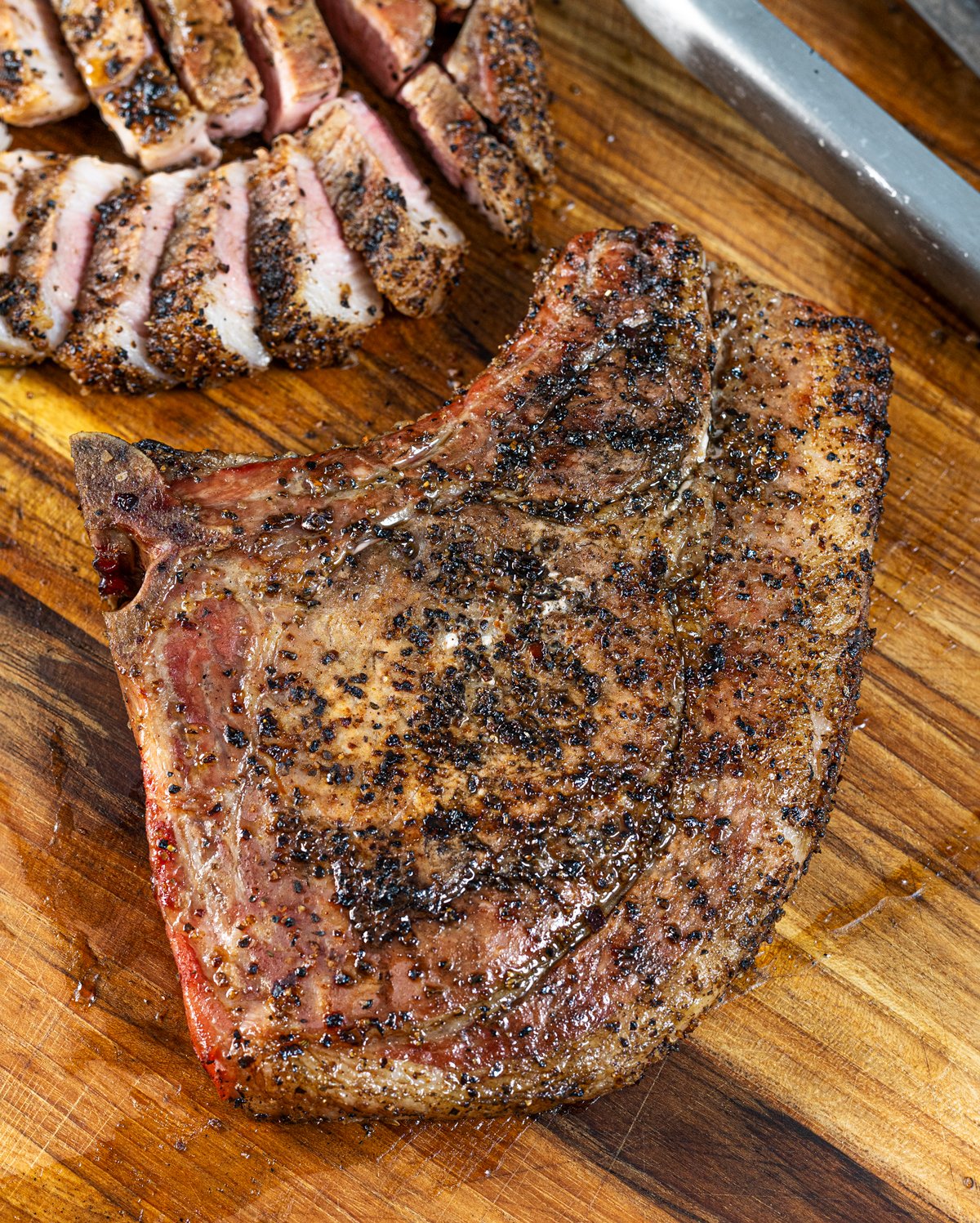 Close up of smoked bone-in pork chop on a wooden board.