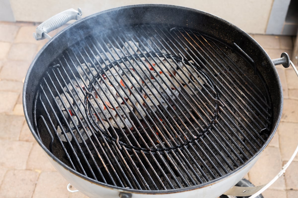 Weber kettle grill with a full bed of lit charcoal briquettes glowing red before setting up two-zone fire