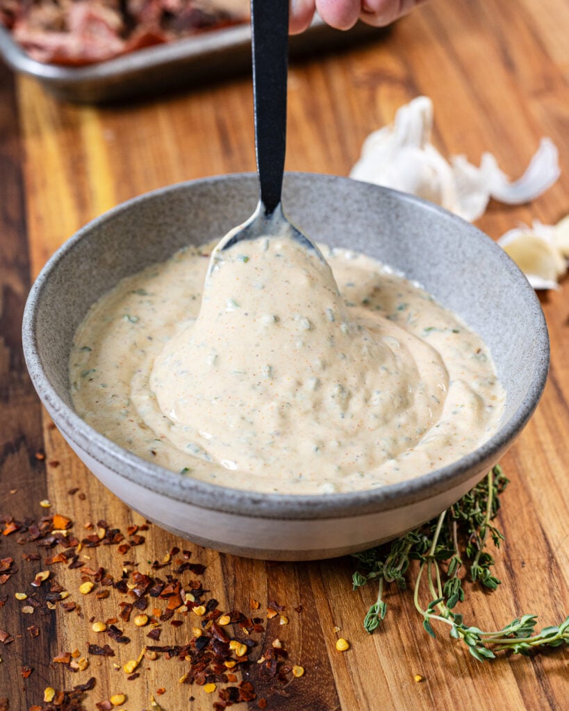 Spoonful of creamy cowboy butter sauce in a bowl surrounded by spices