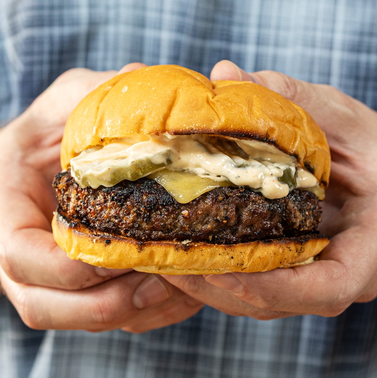 Six charcoal burgers moved to the indirect zone of a Weber kettle grill with American cheese melting
