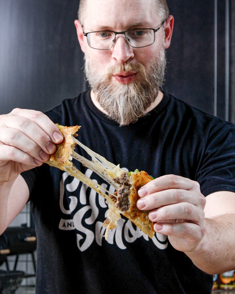 Brad Prose pulling apart a cheesy smash burger taco
