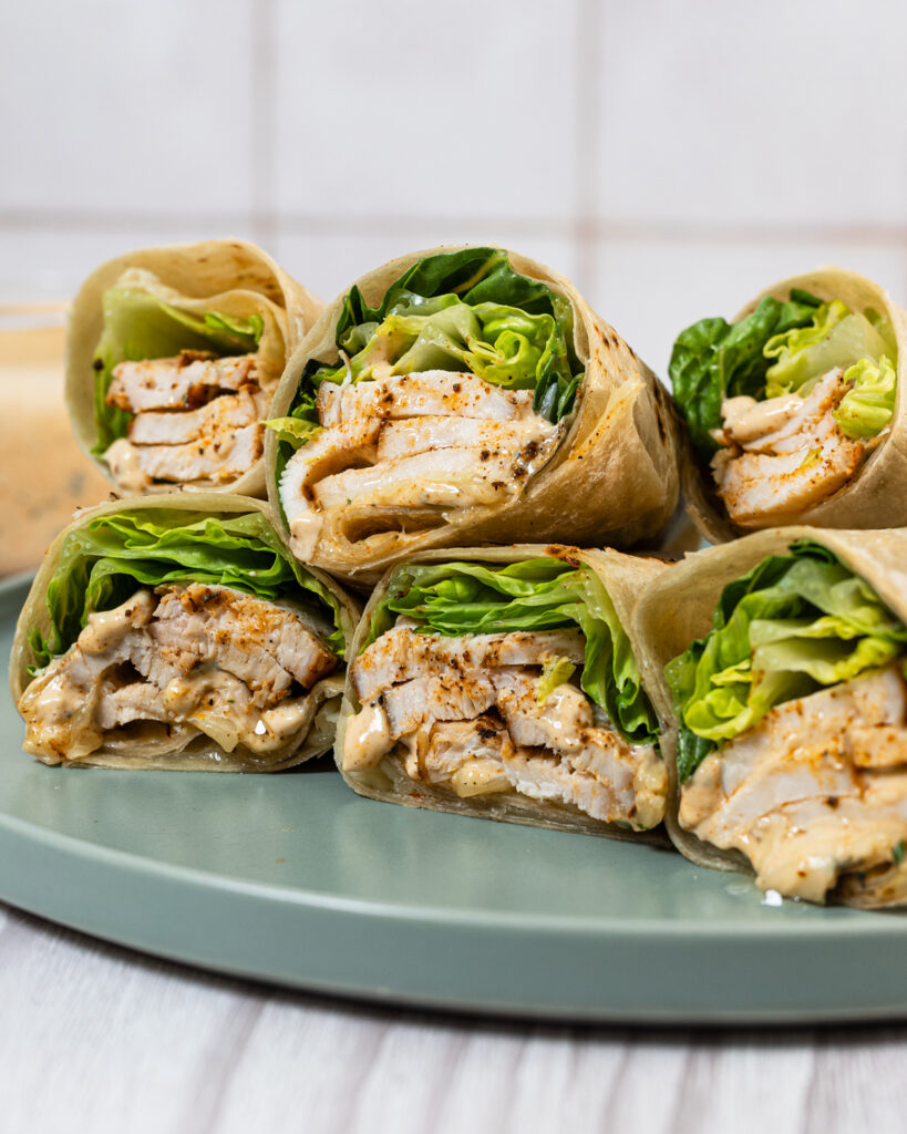 Grilled chicken wraps stacked on top of each other on a plate.