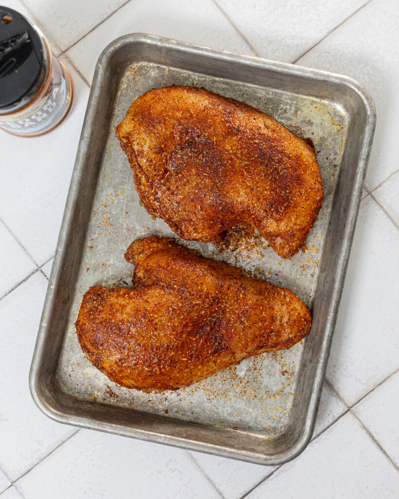Overhead shot of seasoned chicken breasts on a sheet pan.