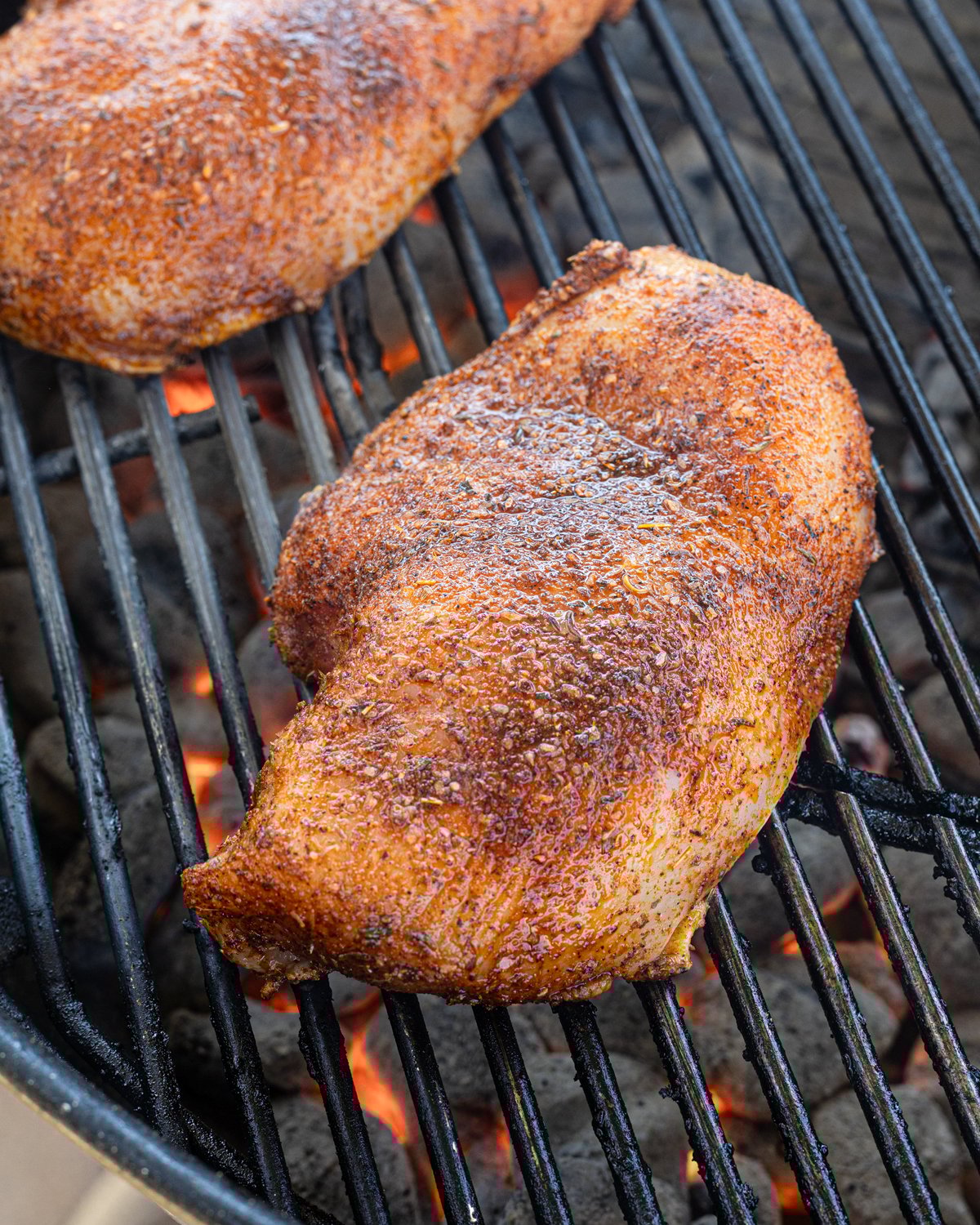Close up of a seasoned chicken breast on the grill.