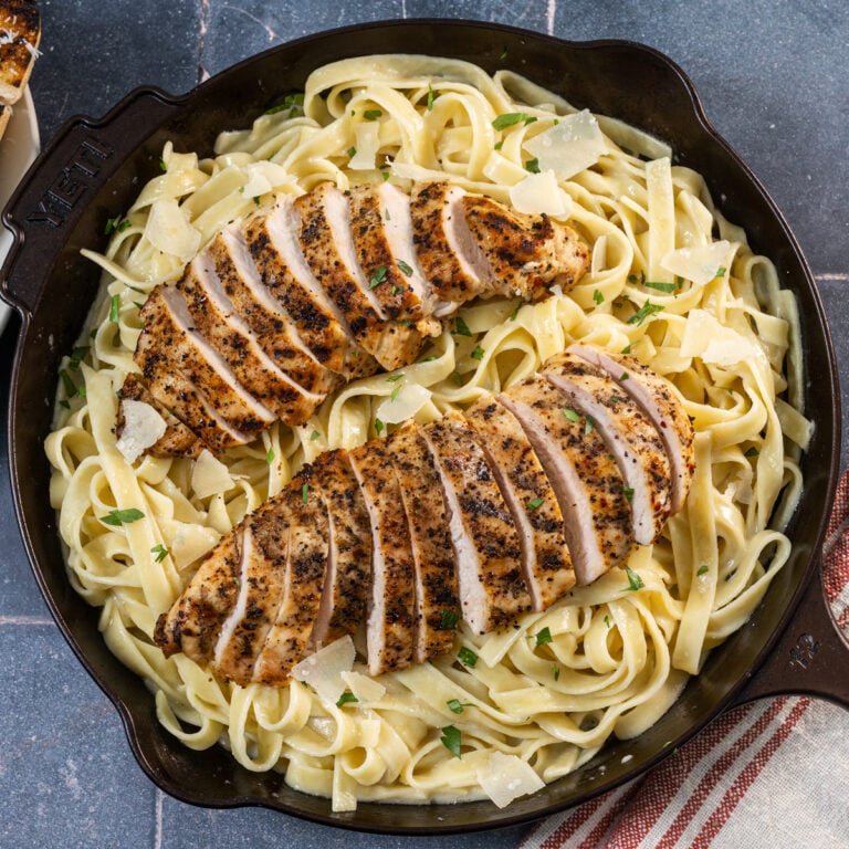 Featuring grilled chicken breast with creamy fettuccini Alfredo in a skillet