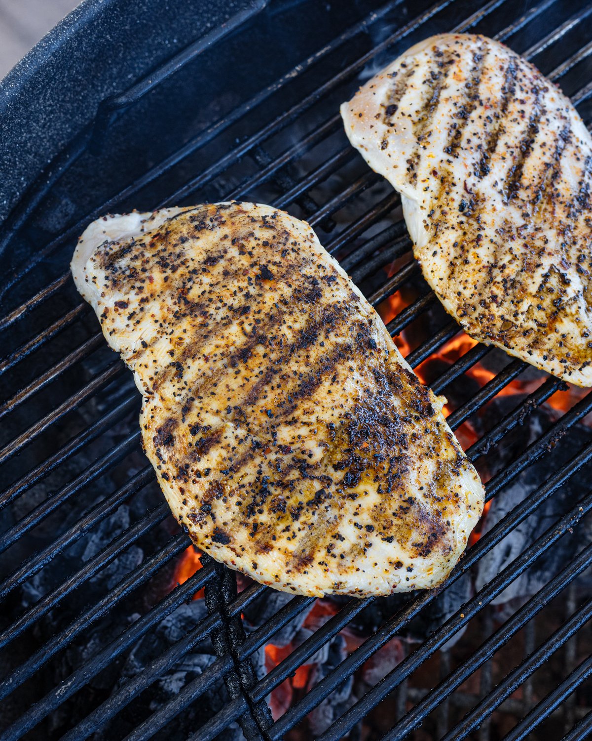 Searing chicken breasts over hot charcoal on the grill