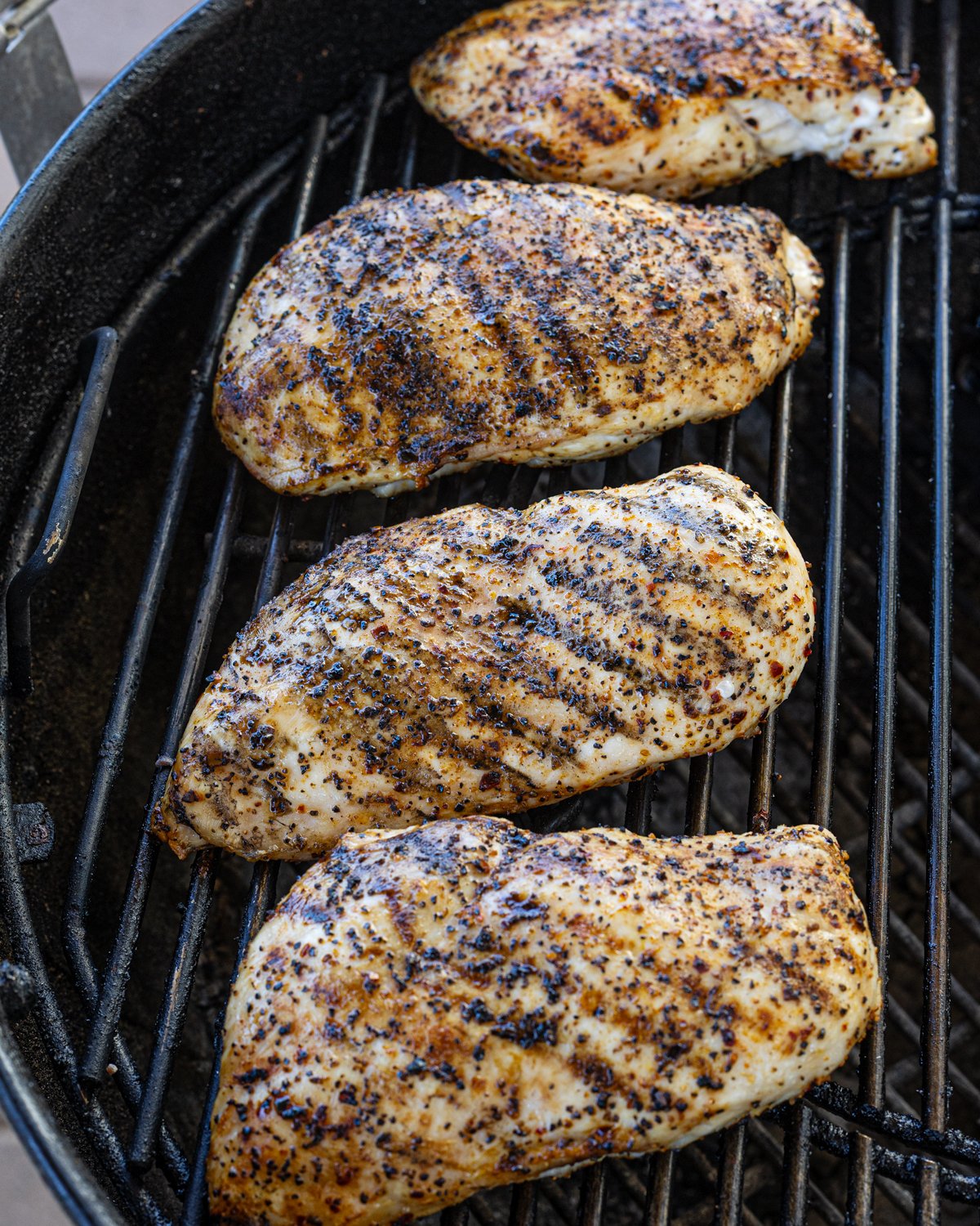 Grilled chicken breasts are resting on the grill