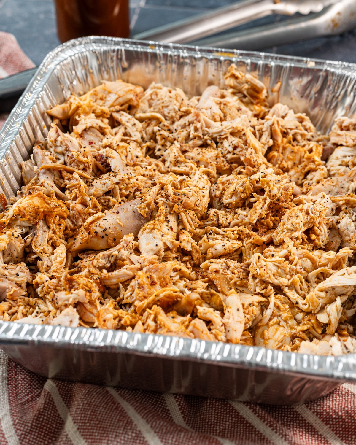 Side view of shredded chicken served in a foil pan.