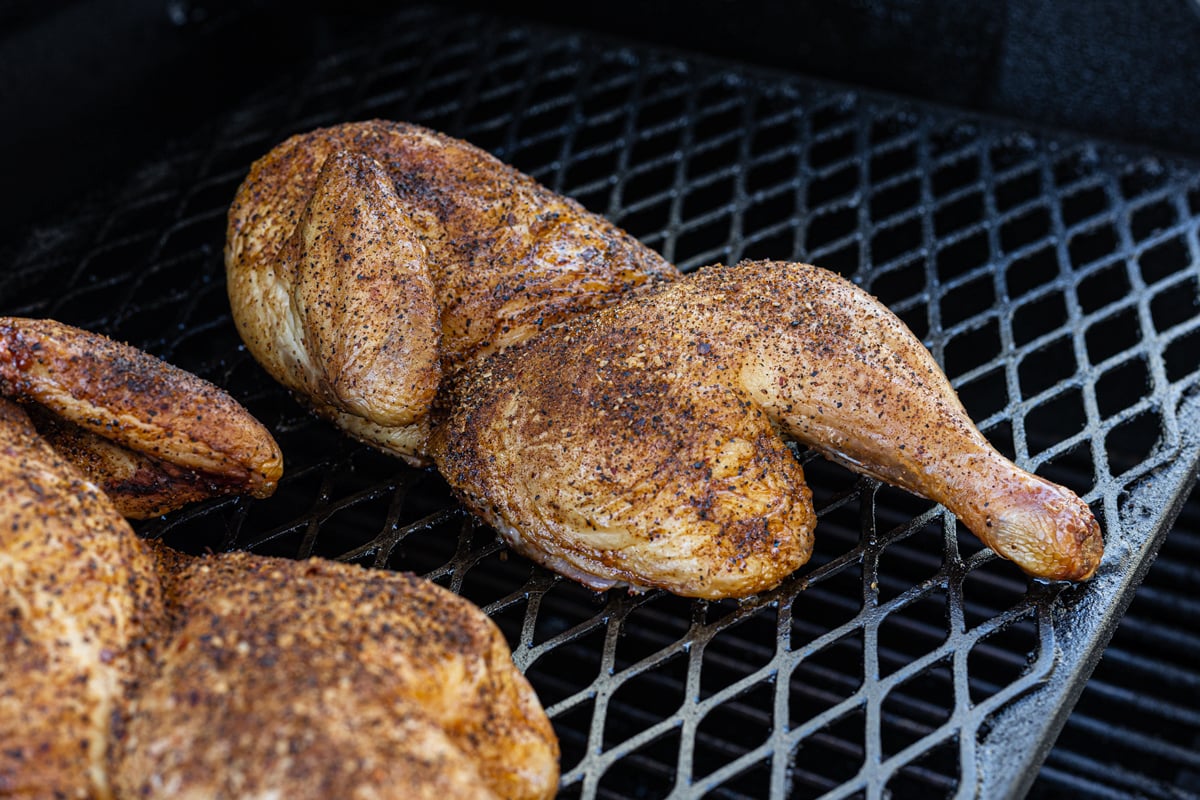 Smoked chicken halves on grill grates to smoke.