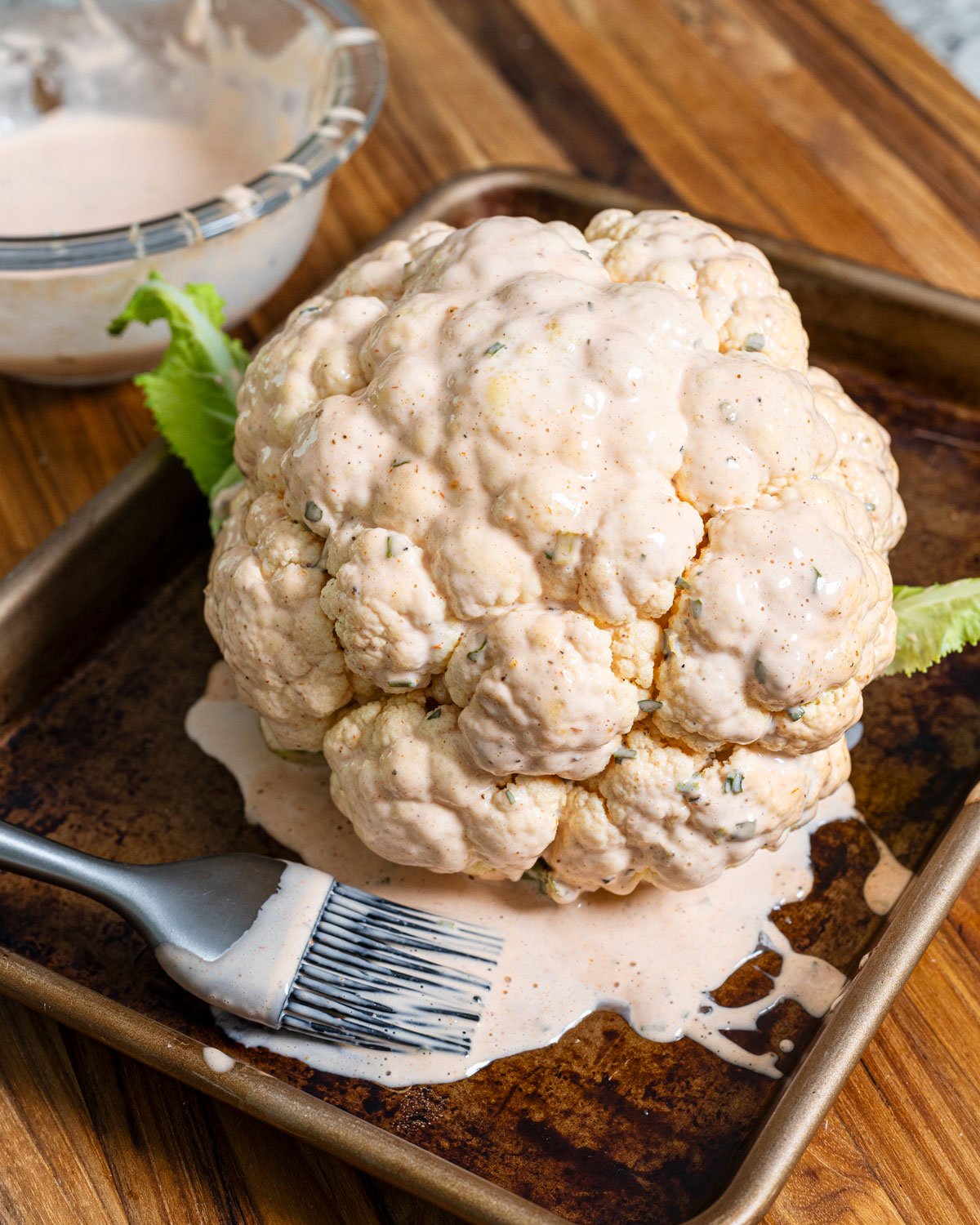 The steamed whole cauliflower is brushed with the buffalo mayo sauce
