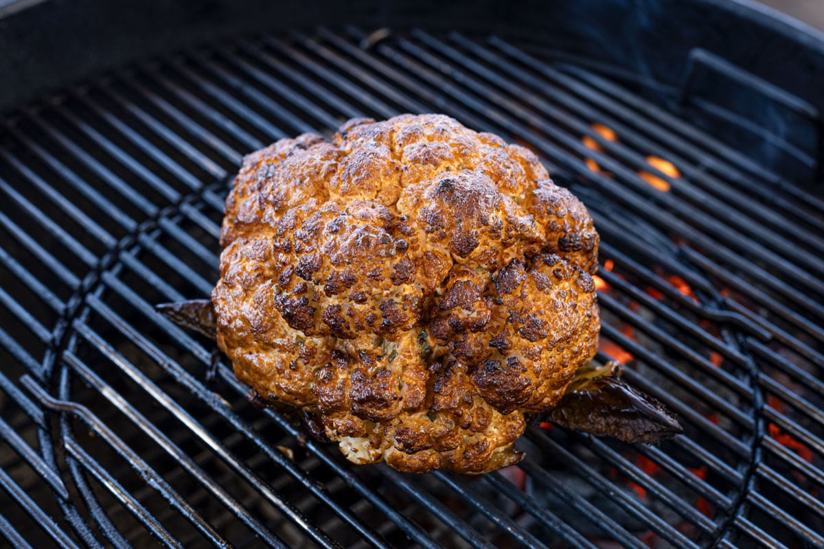 Charred whole cauliflower is on the grill