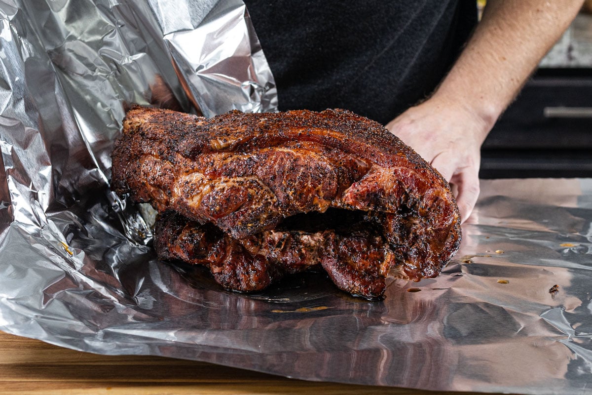 Bark-covered smoked pork butt set on heavy duty foil ready to be double wrapped