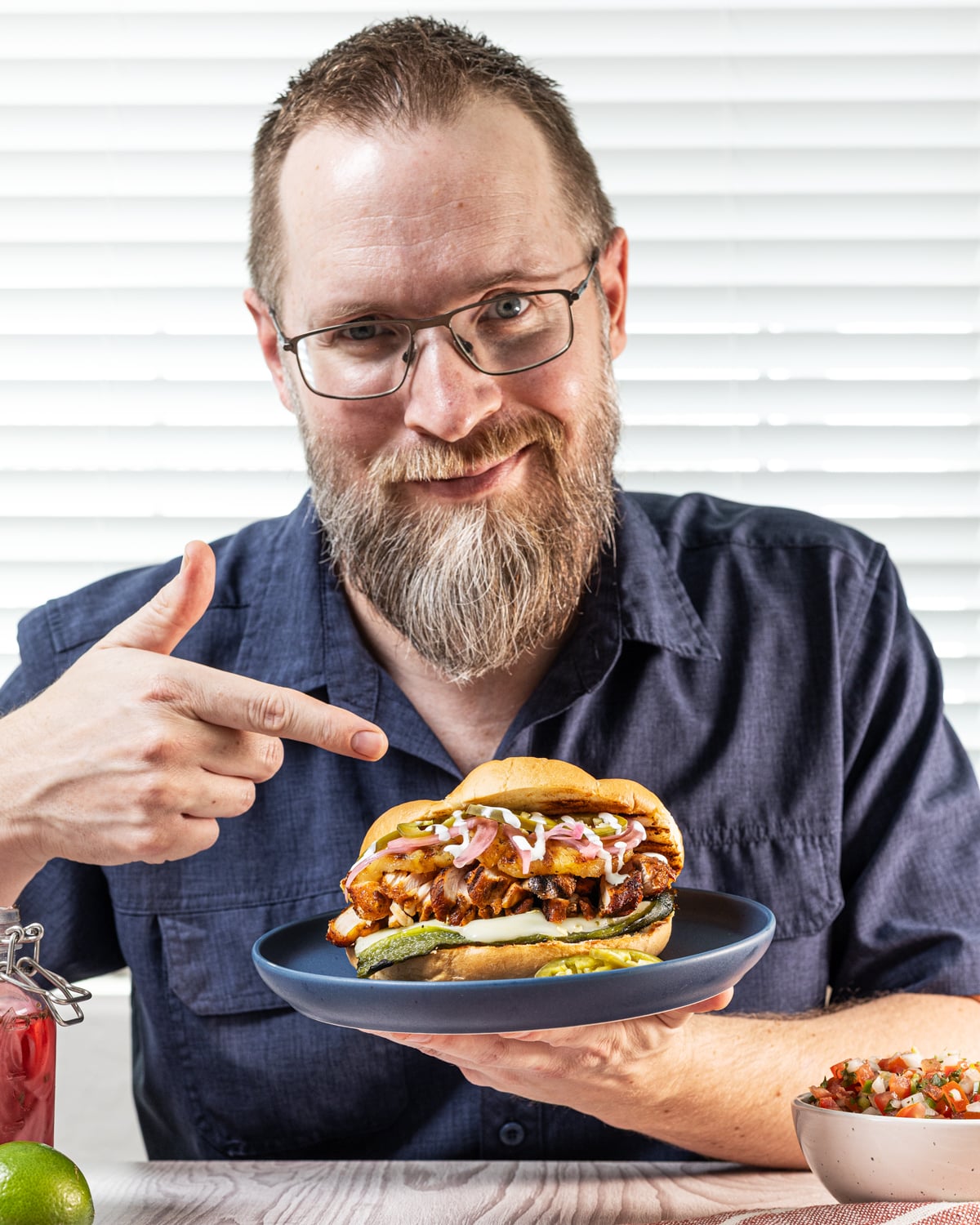 Brad Prose holding a grilled chicken torta on a blue plate