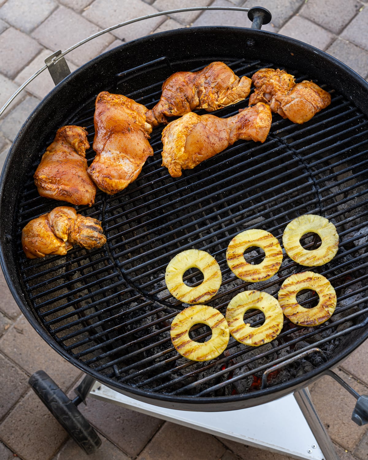 Marinated chicken thighs and pineapple rings on a two-zone charcoal kettle grill