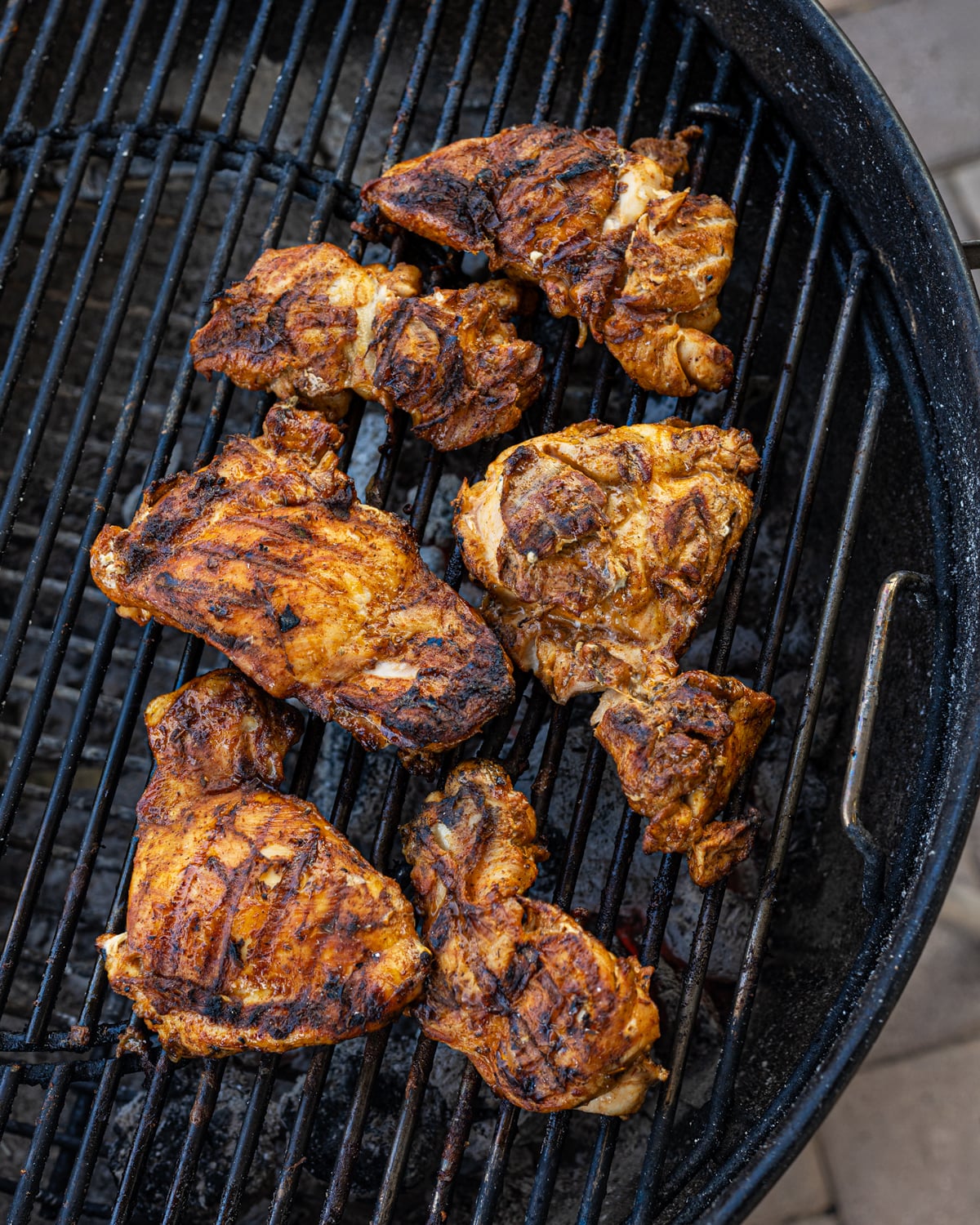 Grilled chicken thighs finishing on the indirect side of a charcoal kettle grill