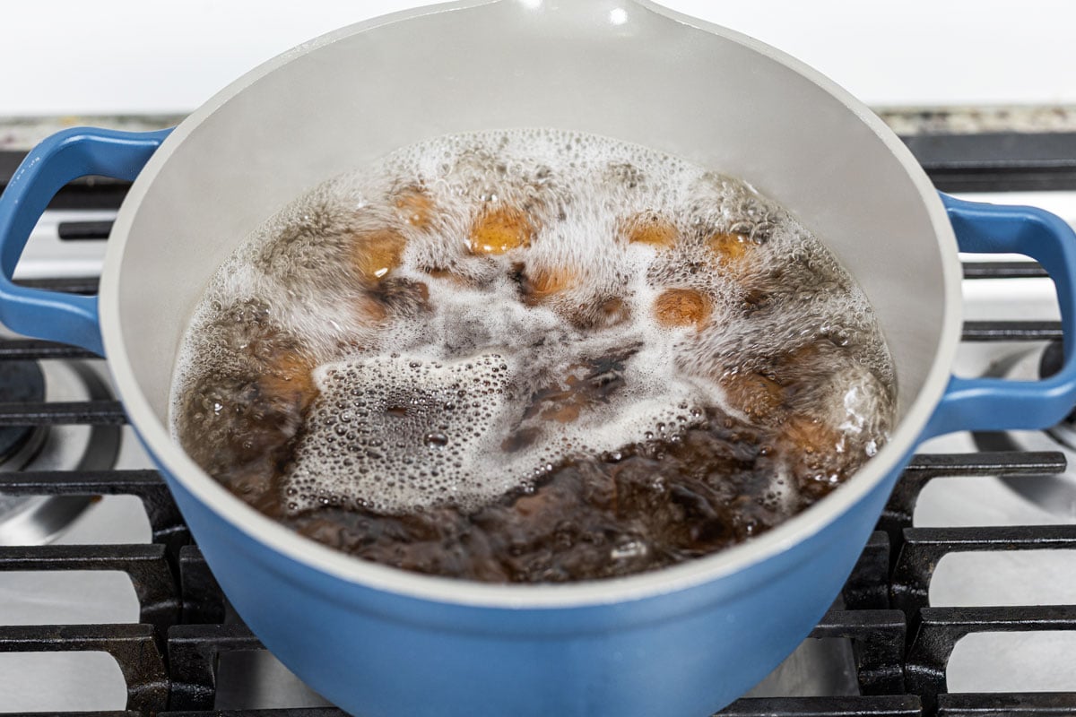 Mini red potatoes boiling in a blue Dutch oven on the stovetop