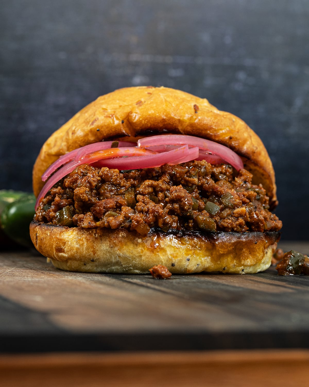 Spicy sweet smoked sloppy joe topped with pickled red onions on a wood board