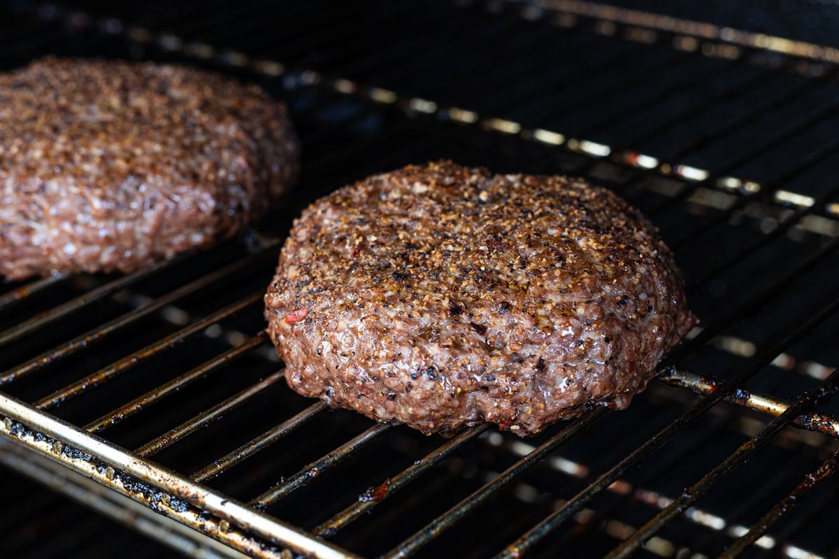 Seasoned beef patties smoking on the grate for sloppy joes
