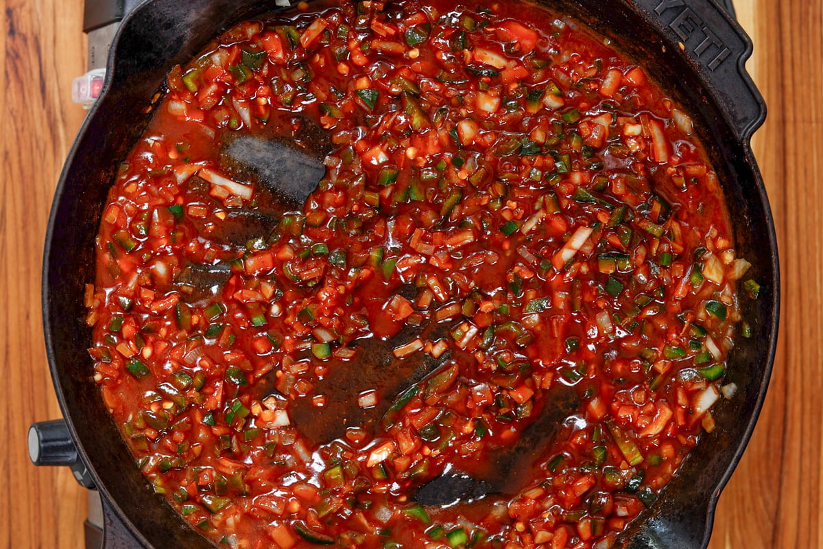 Sloppy joe sauce with poblano, jalapeño, onion, and tomato simmering in a cast iron skillet