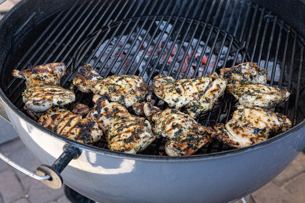 Chicken thighs grilling on the hot side of a two-zone charcoal fire