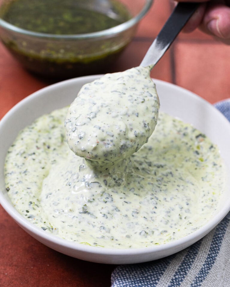 Overhead view of chimichurri mayonnaise in a white bowl with a spoon