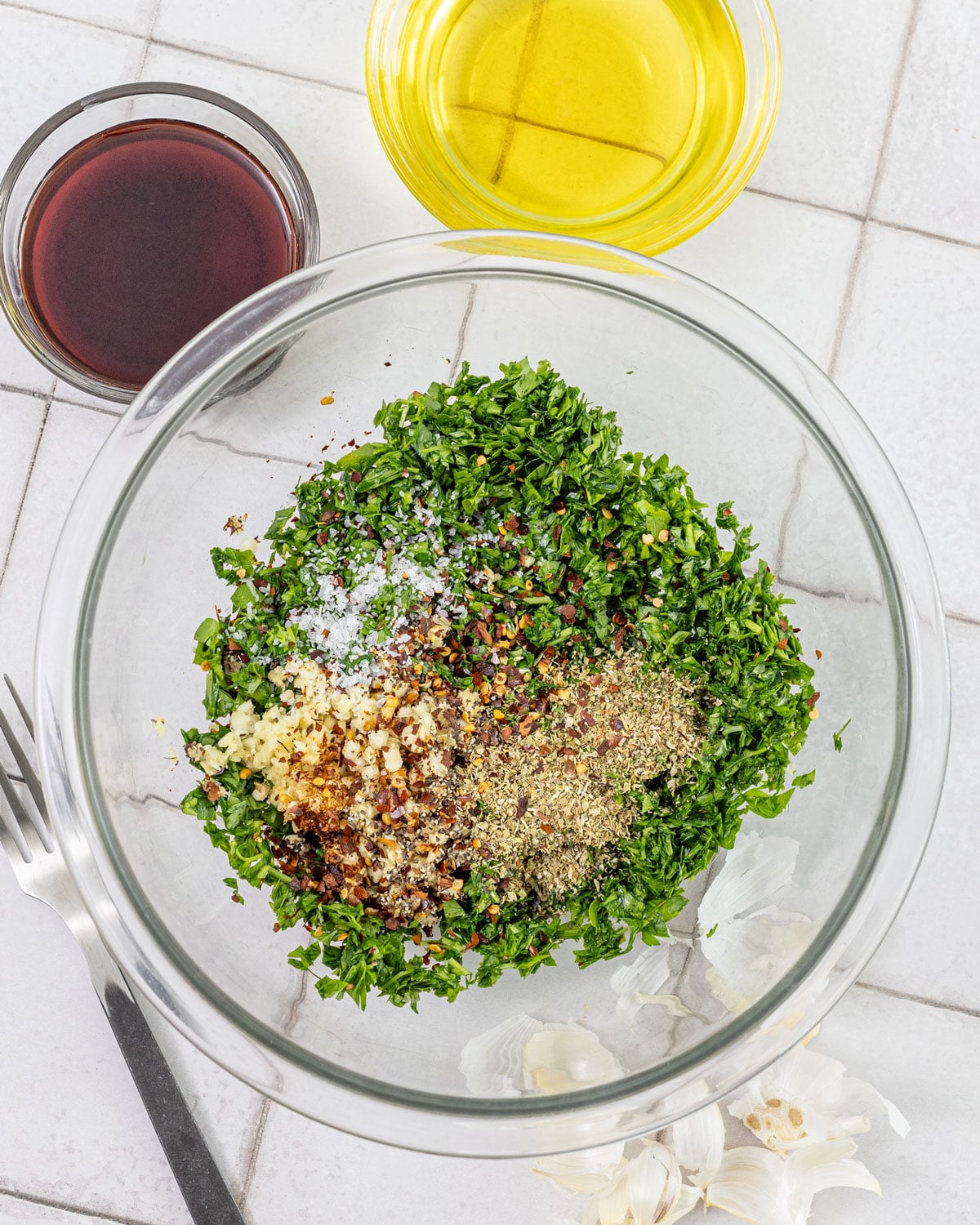 Chopped parsley, minced garlic, oregano, red pepper flakes, and salt in a bowl before mixing