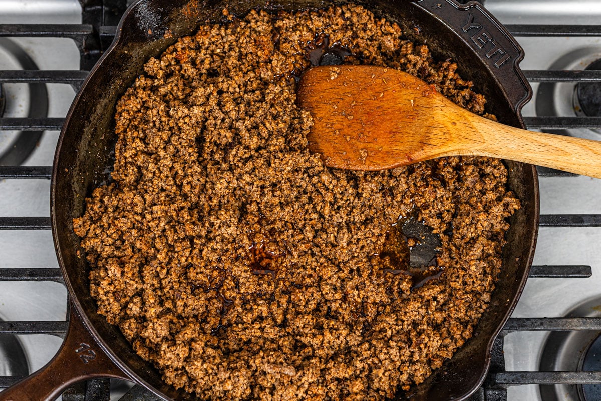 finished seasoned ground beef taco meat with glossy sauce in a cast iron skillet on stove