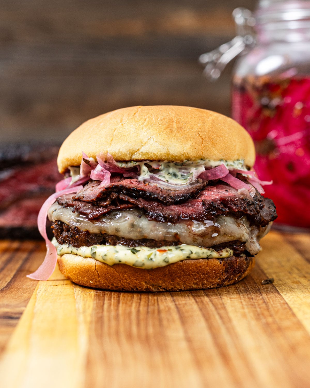 Picanha burger with sliced reverse-seared steak, melted cheese, pickled red onions, and chimichurri mayo on a toasted bun