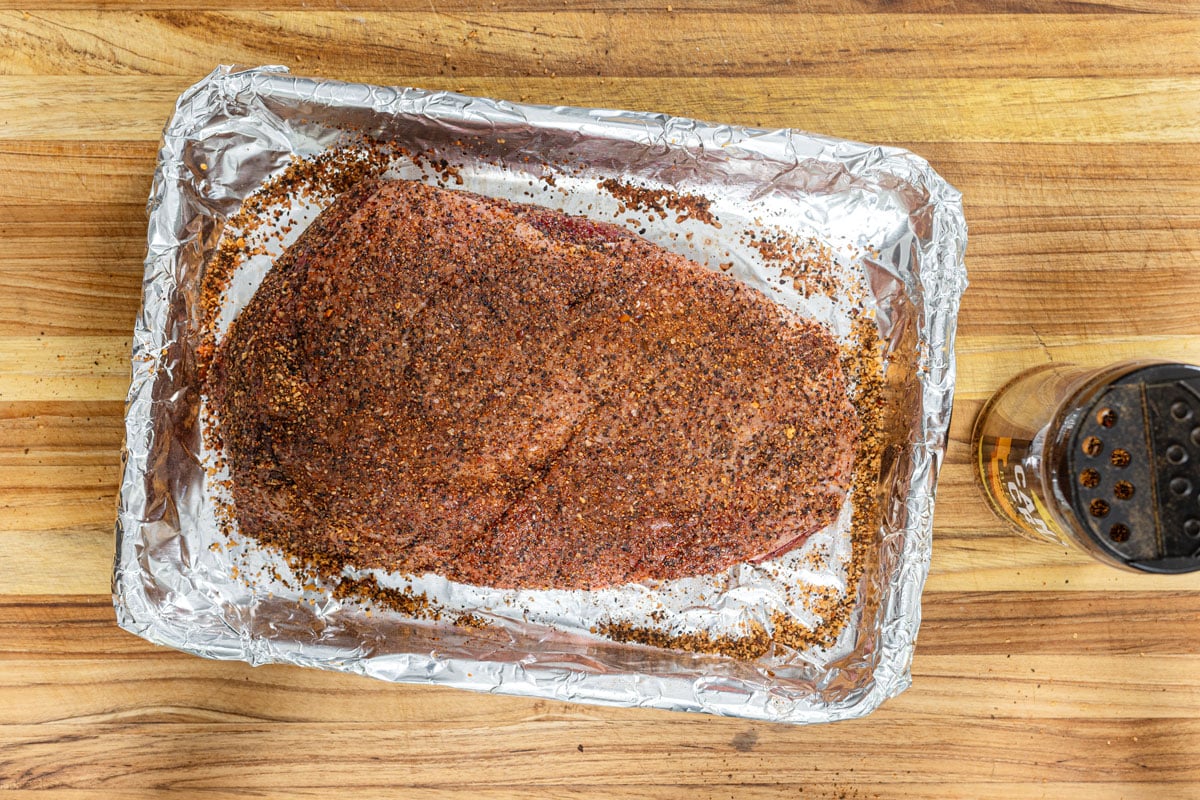 Raw picanha seasoned for a reverse sear on a foil-lined sheet pan