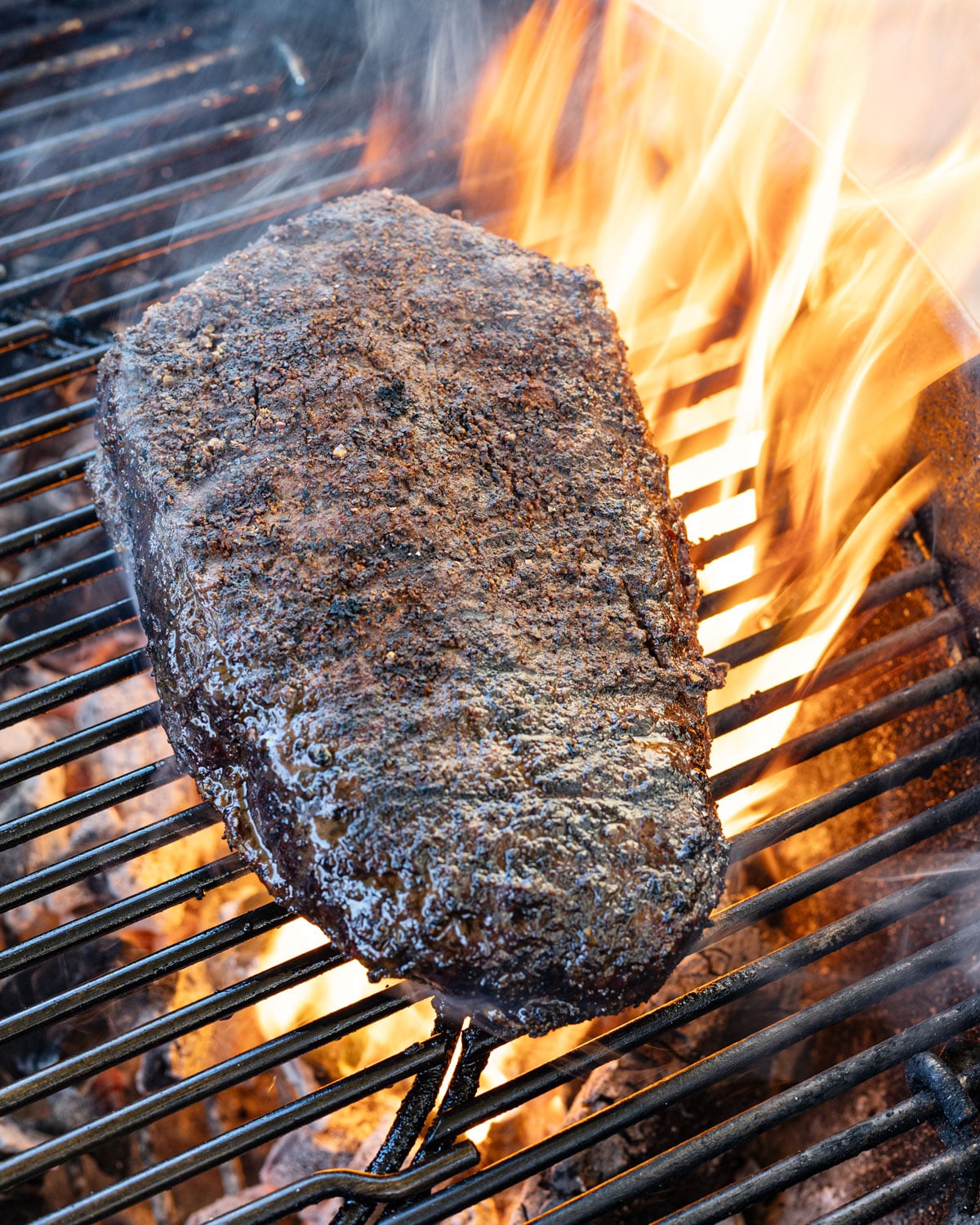 Picanha continuing to sear over open flame with a darker crust